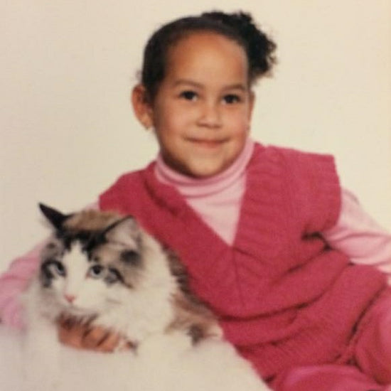 Angelina Vega as a child dressed in all pink while holding a large, fluffy cat