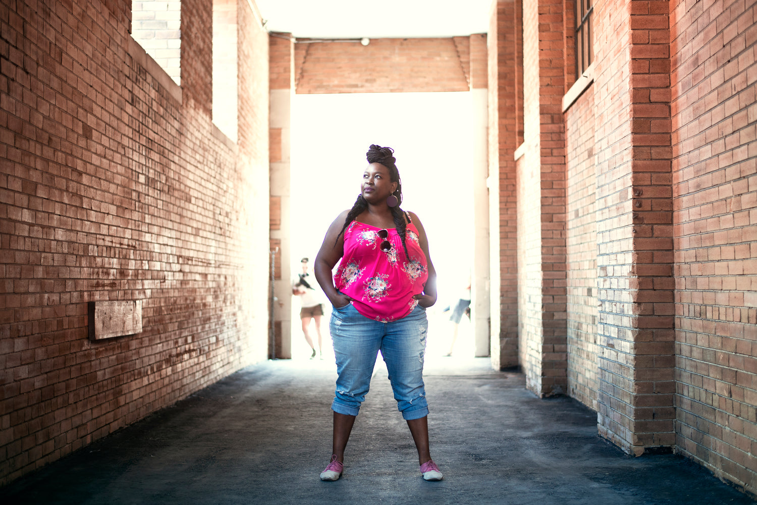 Beautiful Black woman with braids dressed in a bright pink shirt and cropped jeans